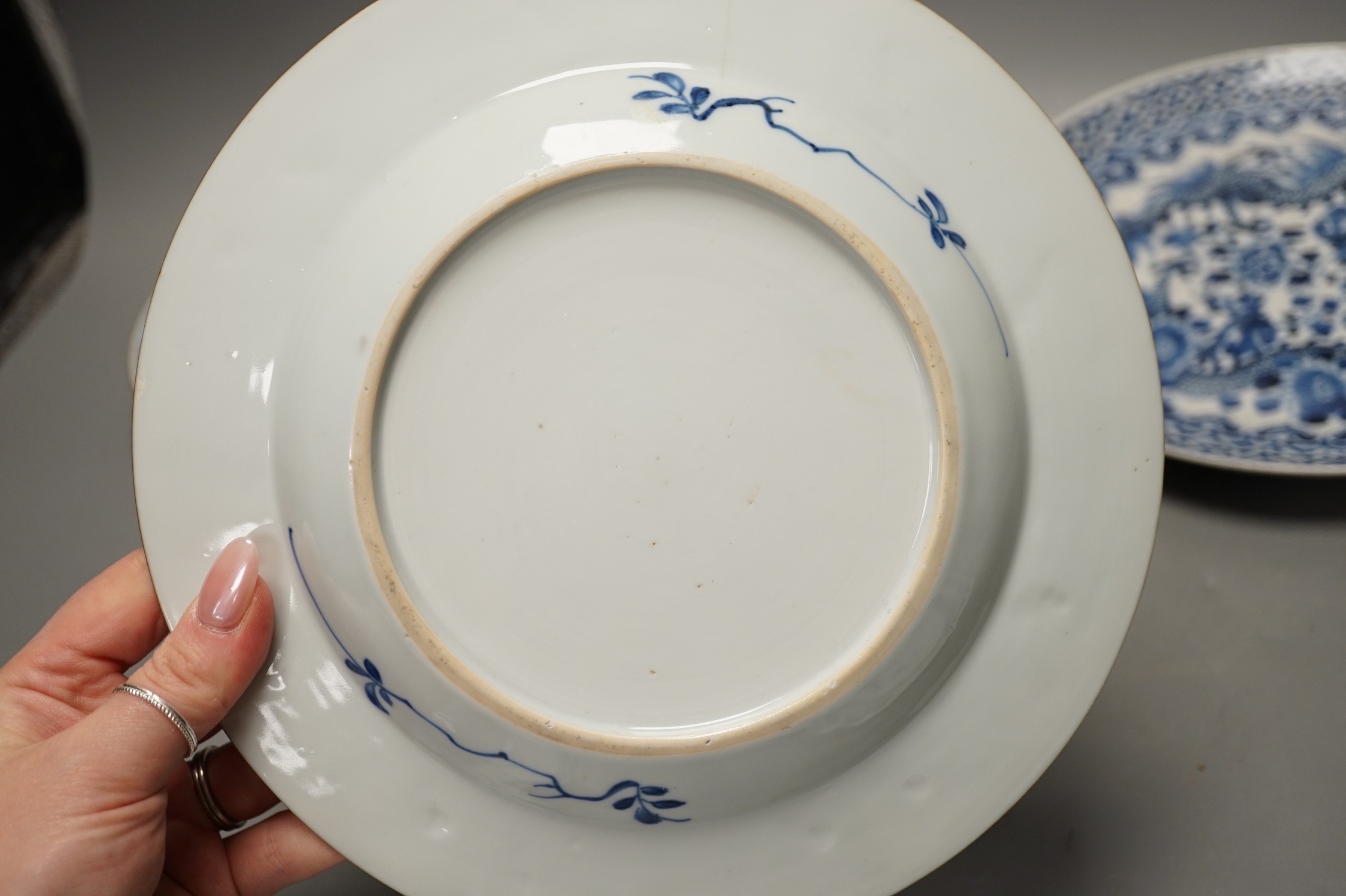 Four Chinese 18th century plates and a late 19th century blue and white dragon plate, largest 24cm diameter